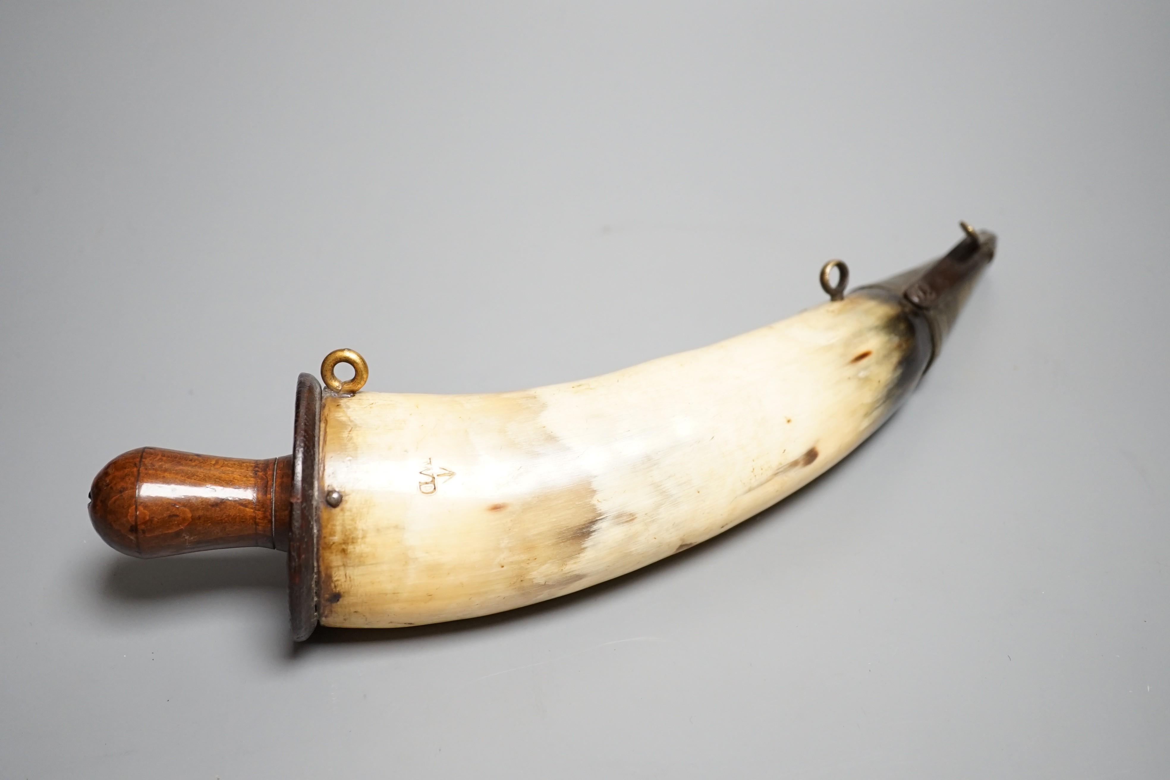 A British military Gunner's powder horn c.1800, cow horn body, sprung brass charger, wooden end cap and plug, two brass suspension rings, body branded with WD stamp and broad arrow. Length 29cms.